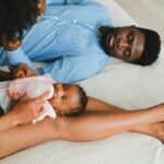 Tender moment with family feeding a baby on bed, showcasing love and togetherness.