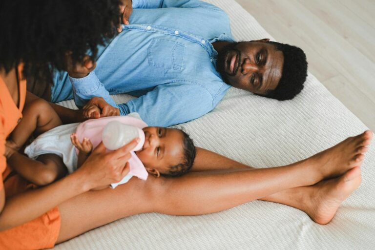 Tender moment with family feeding a baby on bed, showcasing love and togetherness.